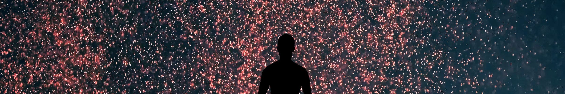 Silhouette of a person standing beneath a sky full of glowing particles